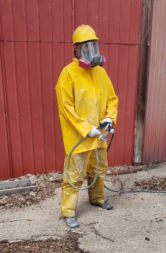 Man in yellow hazardous material suit with gas mask and spray gun